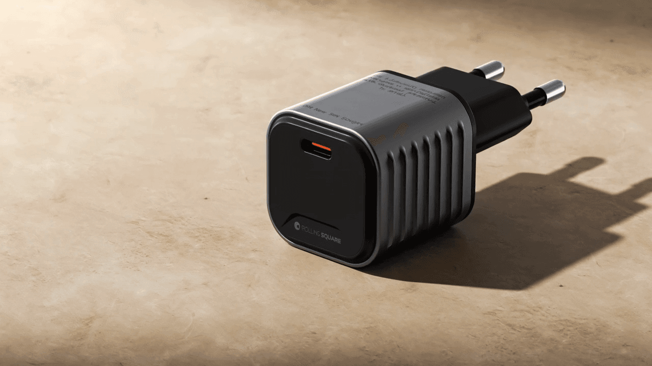 The Rolling Square Super Tiny 65-watt GaN charger on warm cream paper, three-quarter angle.